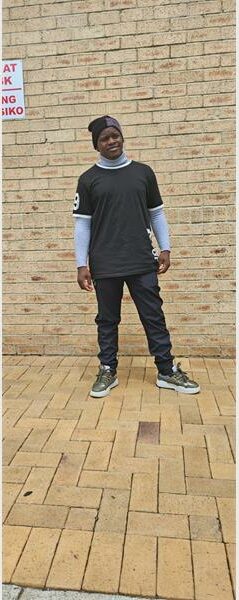 Black man standing in front of a brick wall