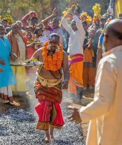 Man in Hindu attire walking over coals