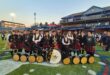 Pipe band members posing with a trophy and their instruments