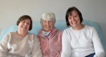 Three women sitting on a couch smiling