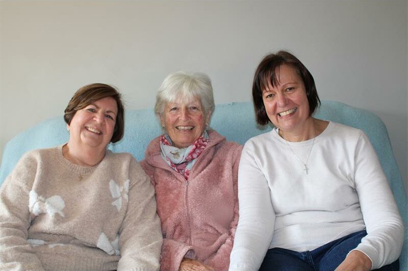 Three women sitting on a couch smiling