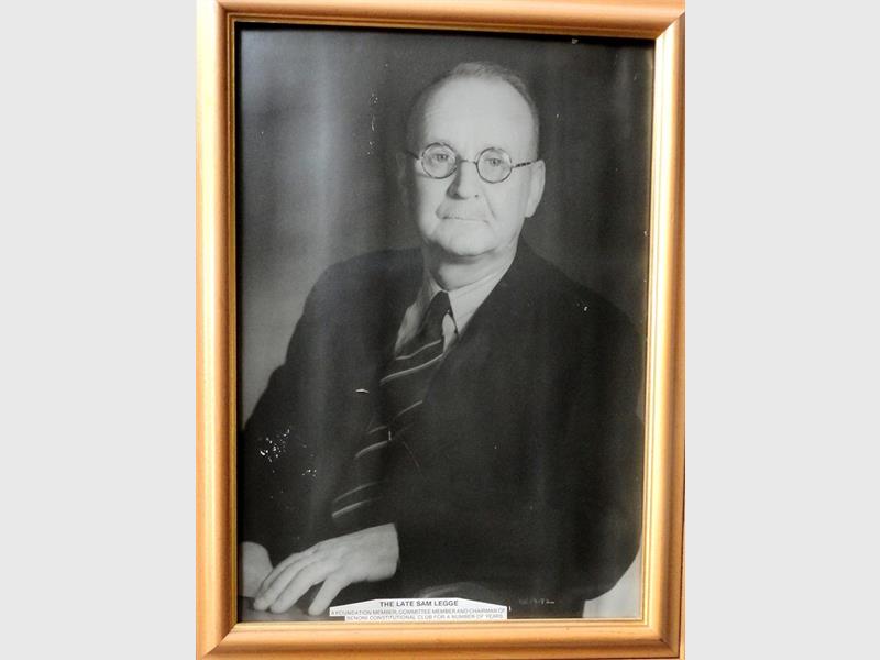 A black and white image of a man wearing a suit and in a photo frame.