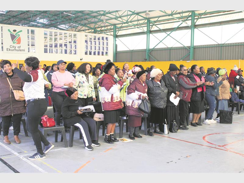 A group of ECD teachers sitting on chairs in a hall. 