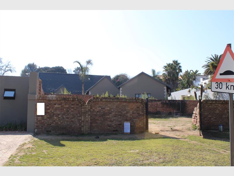 A view of a driveway to a house surrounded by brick walling.