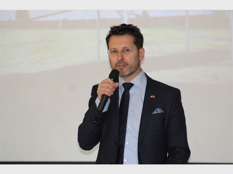 A white man in a suit speaking on a microphone.