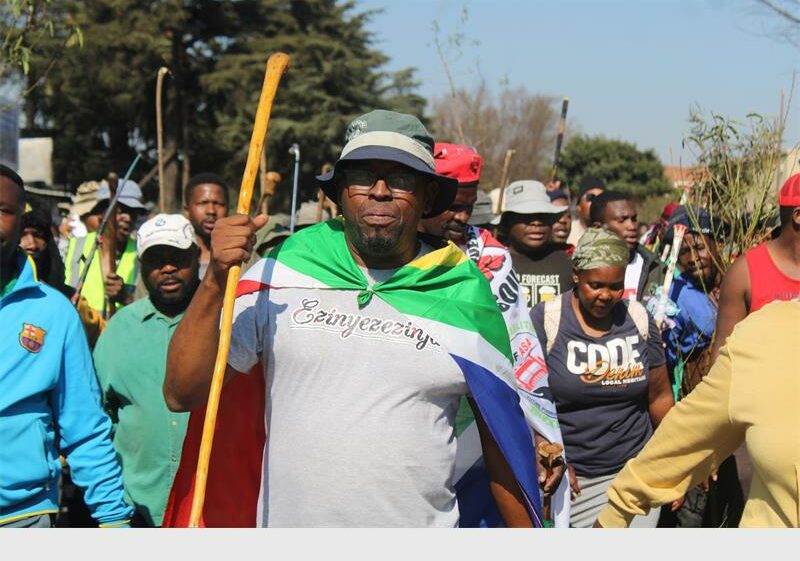Man in a grey top and hat wear a South African Flag
