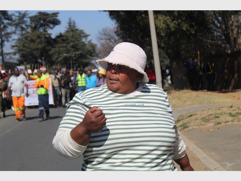 Lady marching in a white and green top with a white hat.