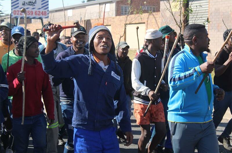 A man in blue overalls, along with other marchers.