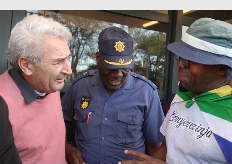 Man in a pink jersey, policeman, and a man in a grey top.