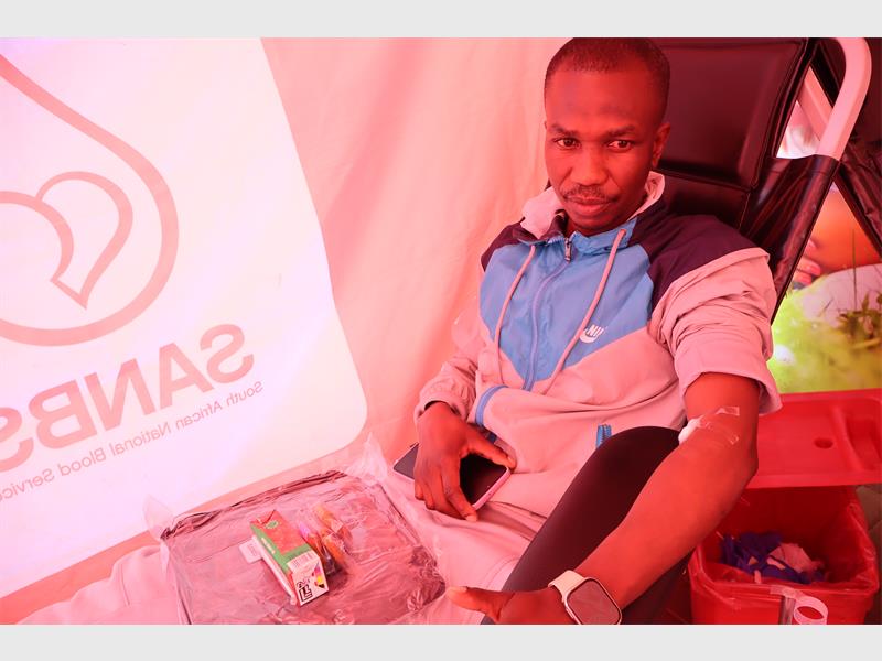A black male on a blood donation chair with a phone in his hand on his lap.