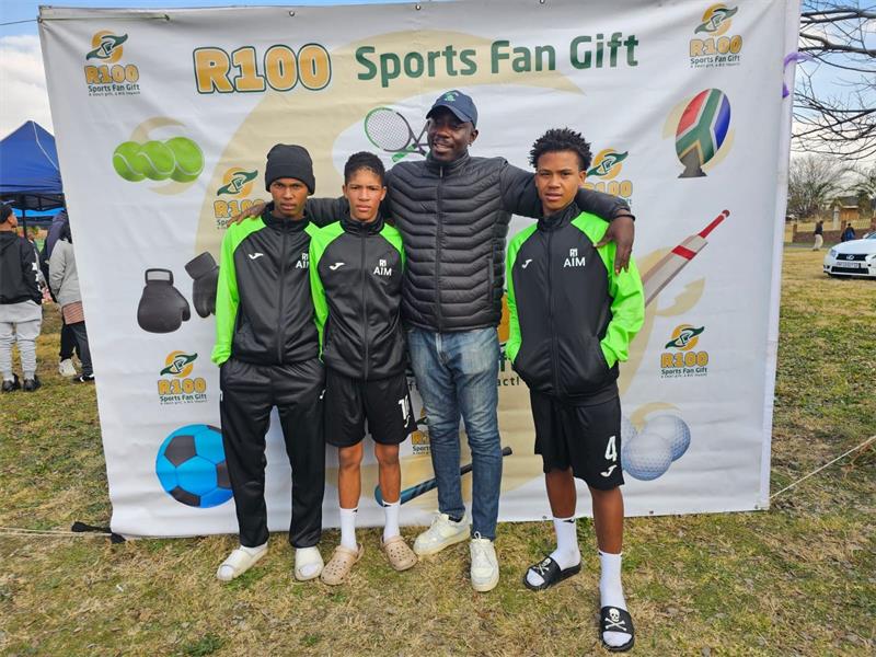 Three young boys in black and green kits, a coach in a black jacket.