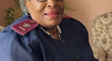 An elderly black woman dressed in a nursing uniform.