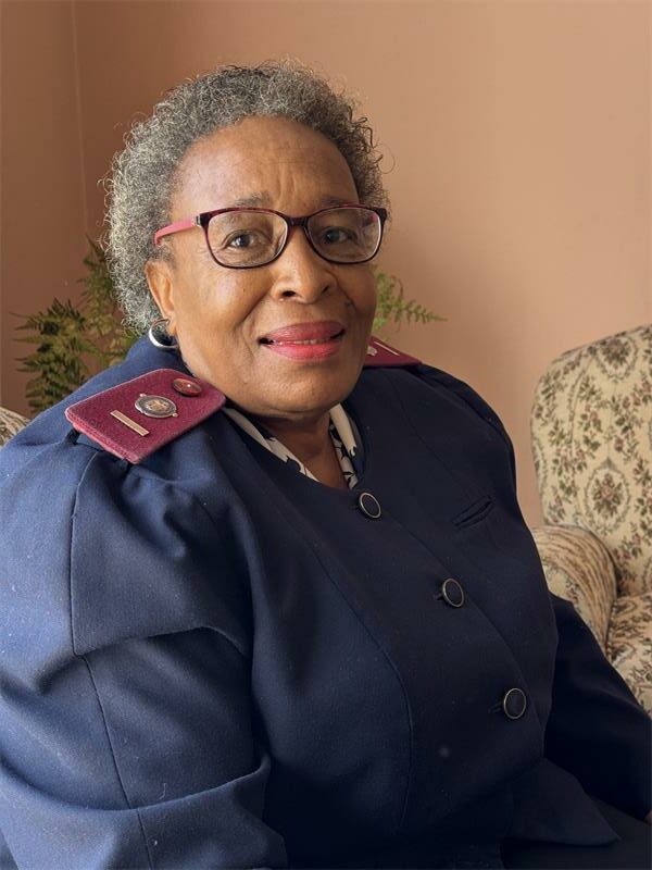 An elderly black woman dressed in a nursing uniform.