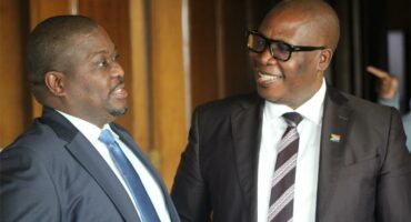 two men standing next to a glass door