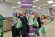 Four women and two men holding DisChem packets and standing in front of a sanitary pad donation box.