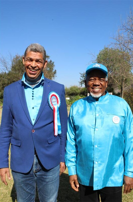 Coloured and black man wearing blue smiles at the camera