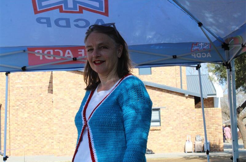 White woman wearing a light blue cardigan standing under an ACDP branded gazebo