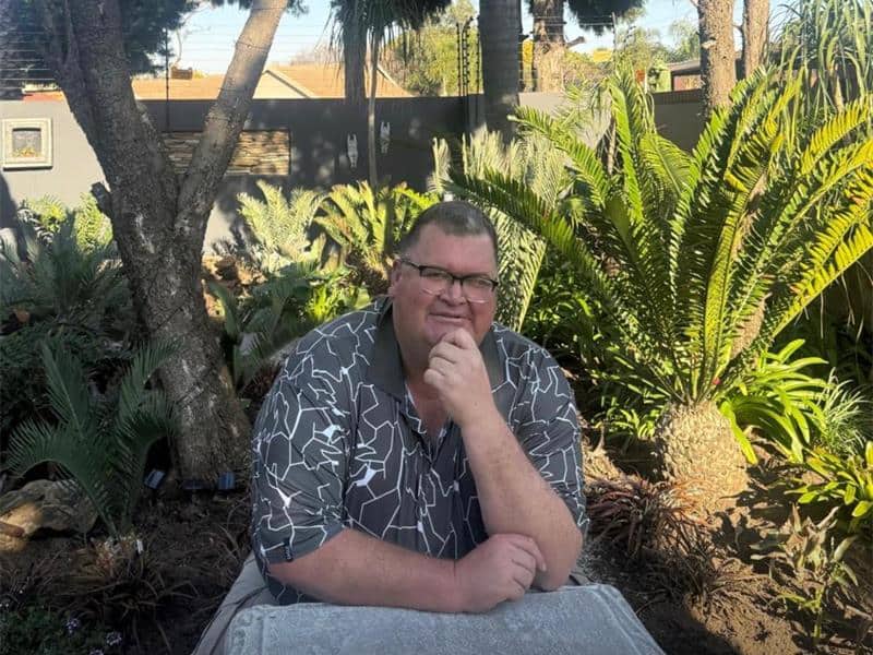 Man sitting at a concrete table with cycads in the background