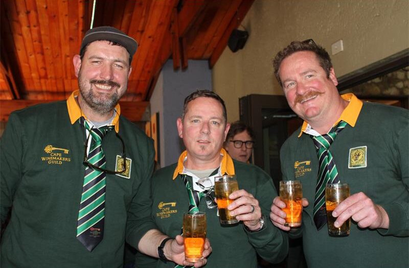 Three men wearing Springbok jerseys and holding glasses