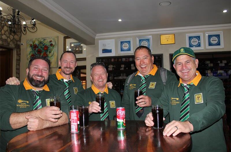 Group of men wearing Springbok jerseys holding glasses