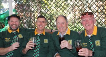 Group of four men wearing Springbok jerseys hold glasses