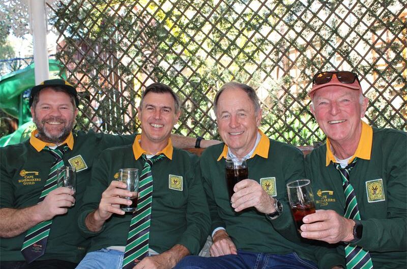 Group of four men wearing Springbok jerseys hold glasses