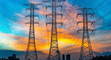 3 electricity pylons photographed with a sunset behind them.
