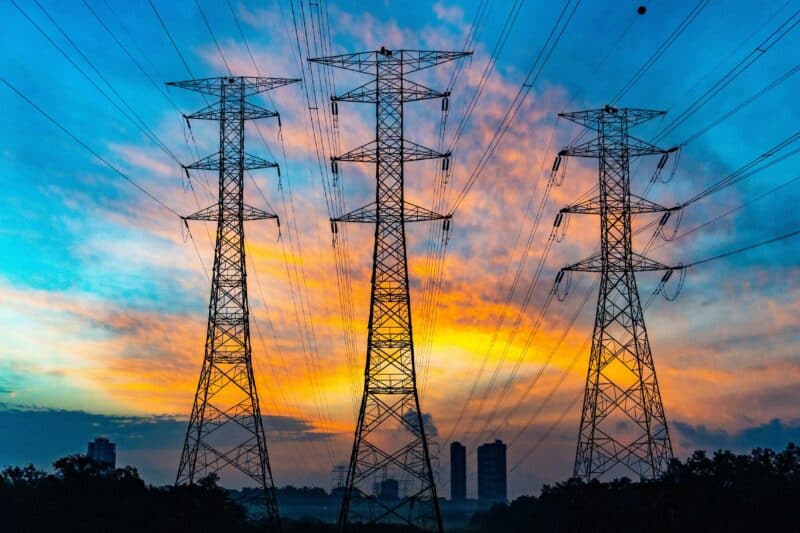 3 electricity pylons photographed with a sunset behind them.