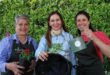 Three women posing with plants, a watering can and hanging basket
