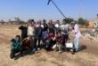 A group of black youths gathered in various poses with one holding a long microphone.