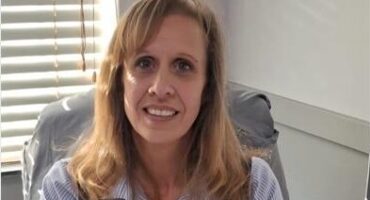 White woman sitting behind a desk