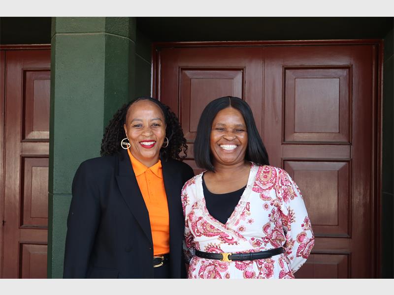 two women standing next to a hall entrance