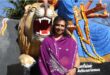Indian woman wearing a purple sari sitting in front of a religious statue