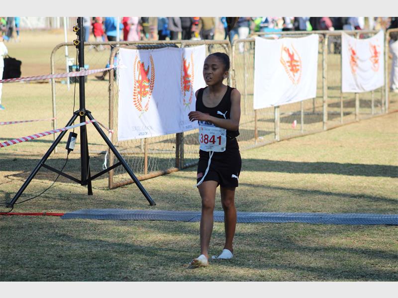 A young female athlete dressed in black taking part in a race.