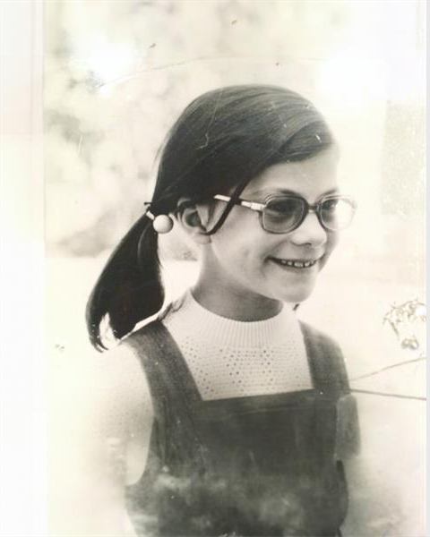A black and white photo of a young girl with pigtails and glasses.