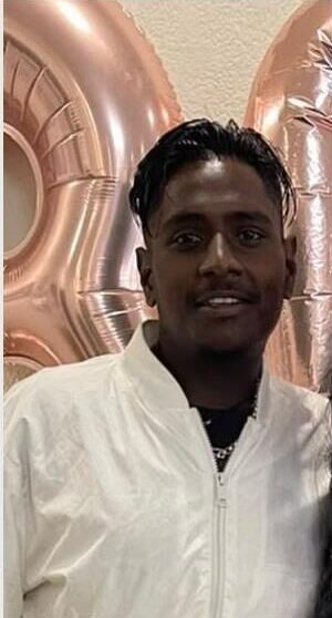 Young Indian man wearing a white shirt standing in front of balloons