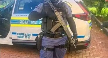 a policed officer in full uniform and carrying a rifle