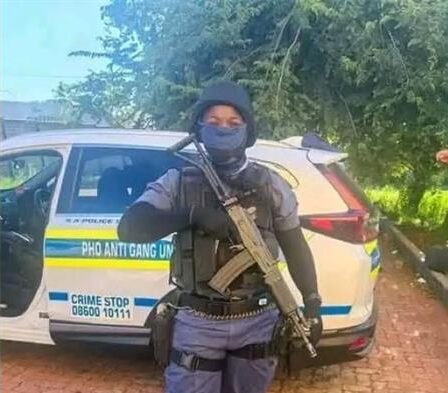 a policed officer in full uniform and carrying a rifle