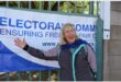 a woman standing next to an IEC banner