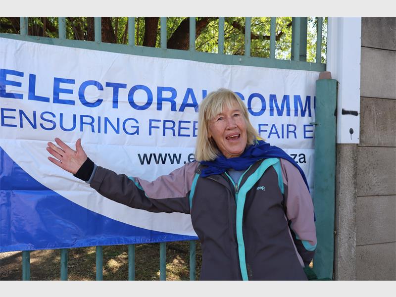 a woman standing next to an IEC banner