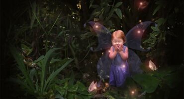 A fairy garden with lights and a fairy.