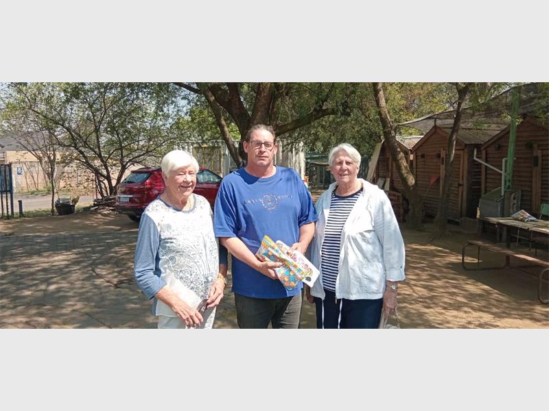 A white man holding pencil cases flanked by two white women.
