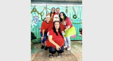 A group of people wearing Christmas shirts and hats.