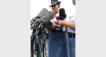 Two black SAPS females in uniform speaking into media microphones