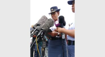 Two black SAPS females in uniform speaking into media microphones