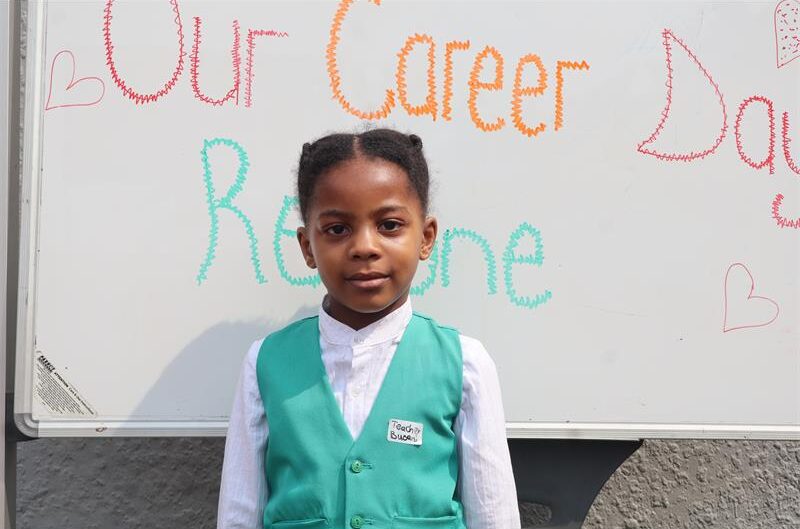A young girl dressed in a green teachers suit  