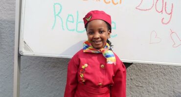 A small girl dressed in red airhostess clothes