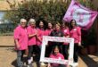Group of women dressed in pink, holding a banner and photo frame