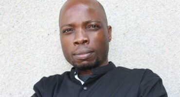 A head and shoulders photo of a black male wearing a black shirt and looking at the camera