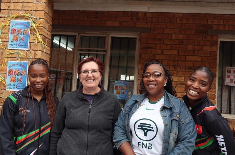 Four ladies standing next to each other smiling